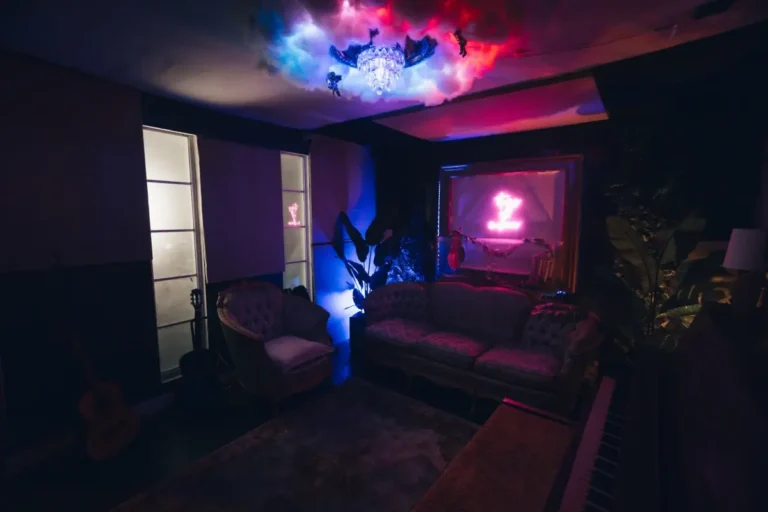 Artist lounge at Ocean Blue Recording in Decatur, GA with vintage couch, neon sign, cloud chandelier, upright piano and acoustic guitar