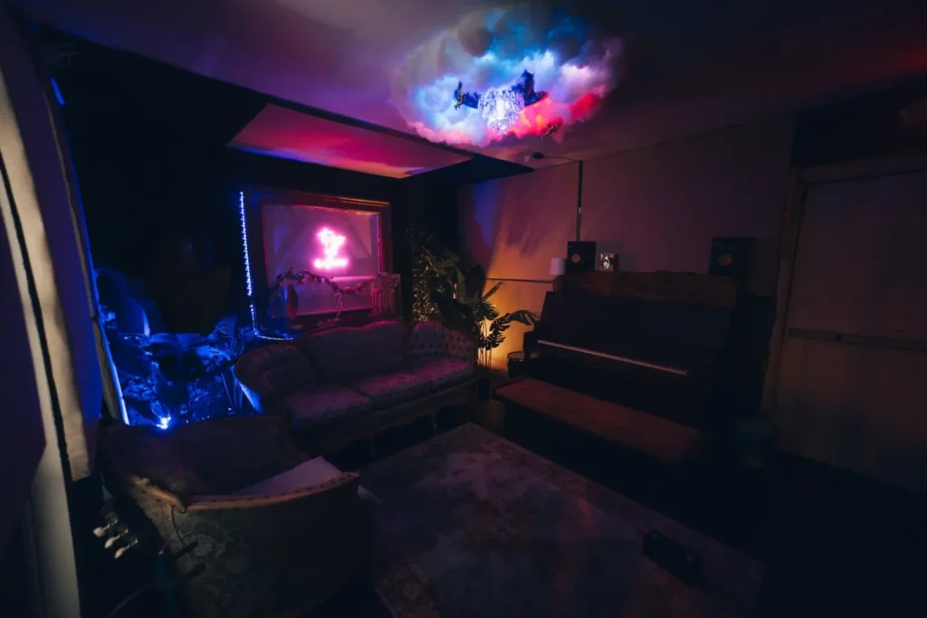 Wide-angle view of the artist lounge at Ocean Blue Recording near Atlanta, GA with couches, piano and neon sign